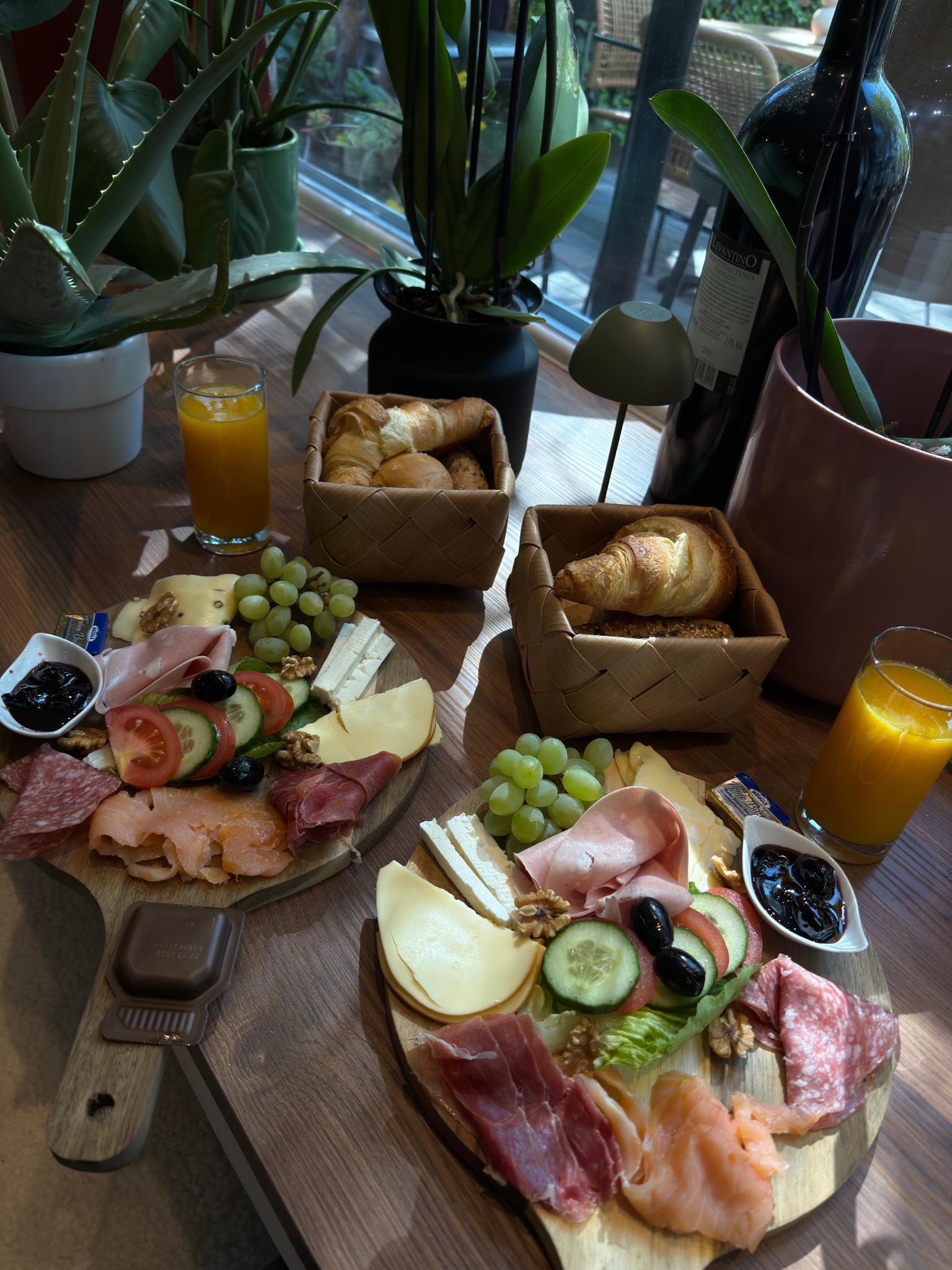 Frühstück am Fenster: zwei Brettchen, Croissants im Körbchen und Orangensaft